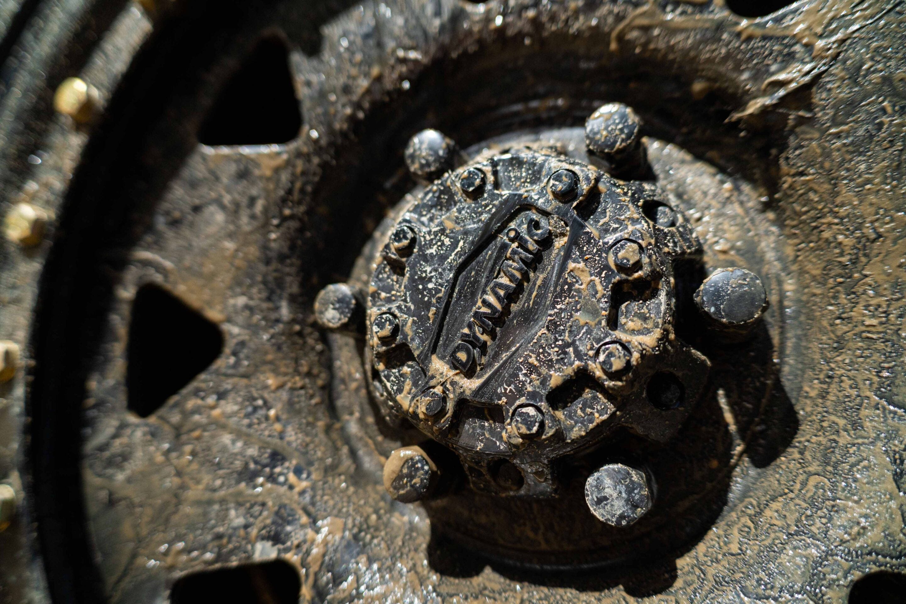 Close-up of a muddy bicycle crankset with bolts and a mud-caked chainring.