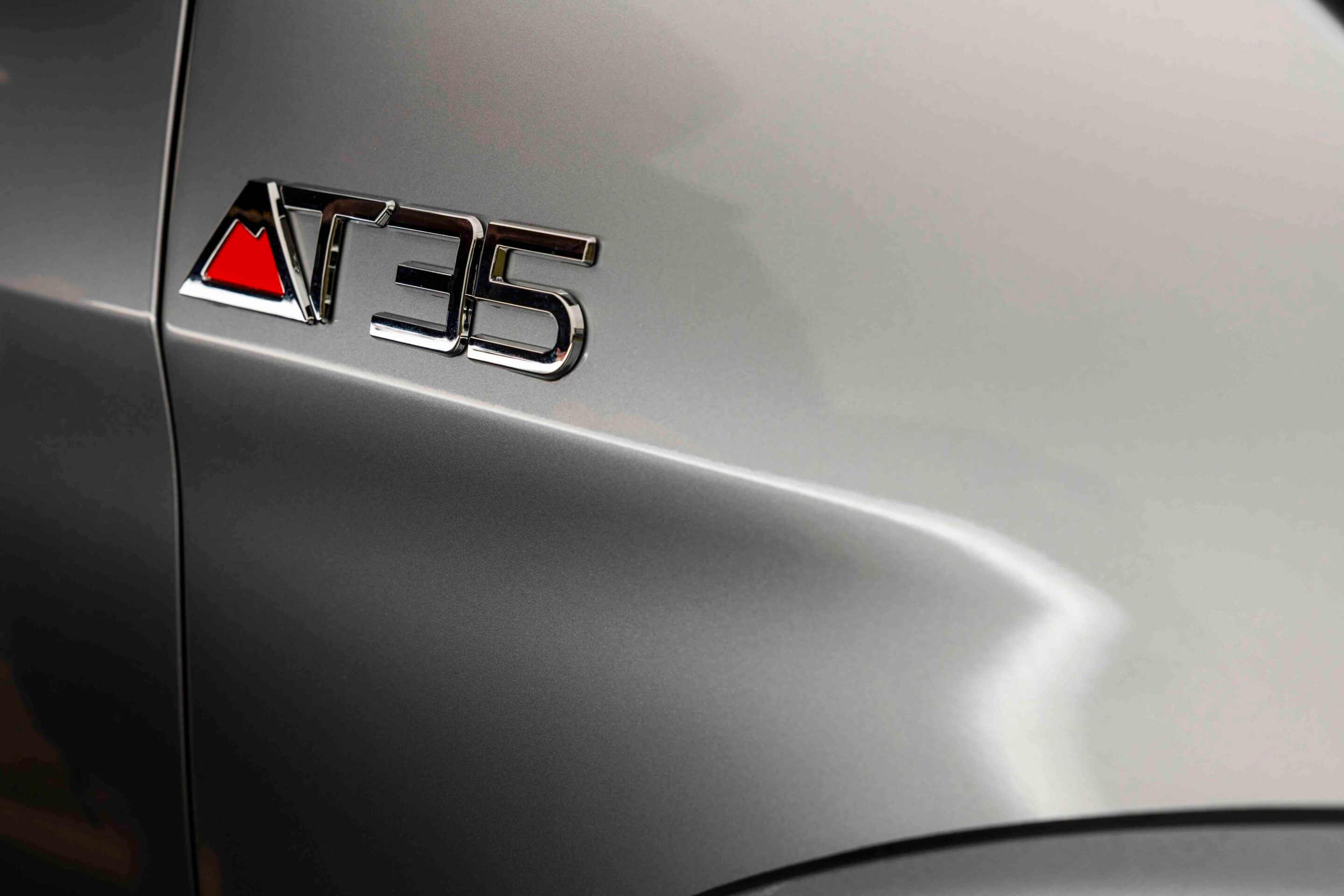 Close-up of the chrome 'S5' badge on a metallic gray car body with a small red triangular accent piece.