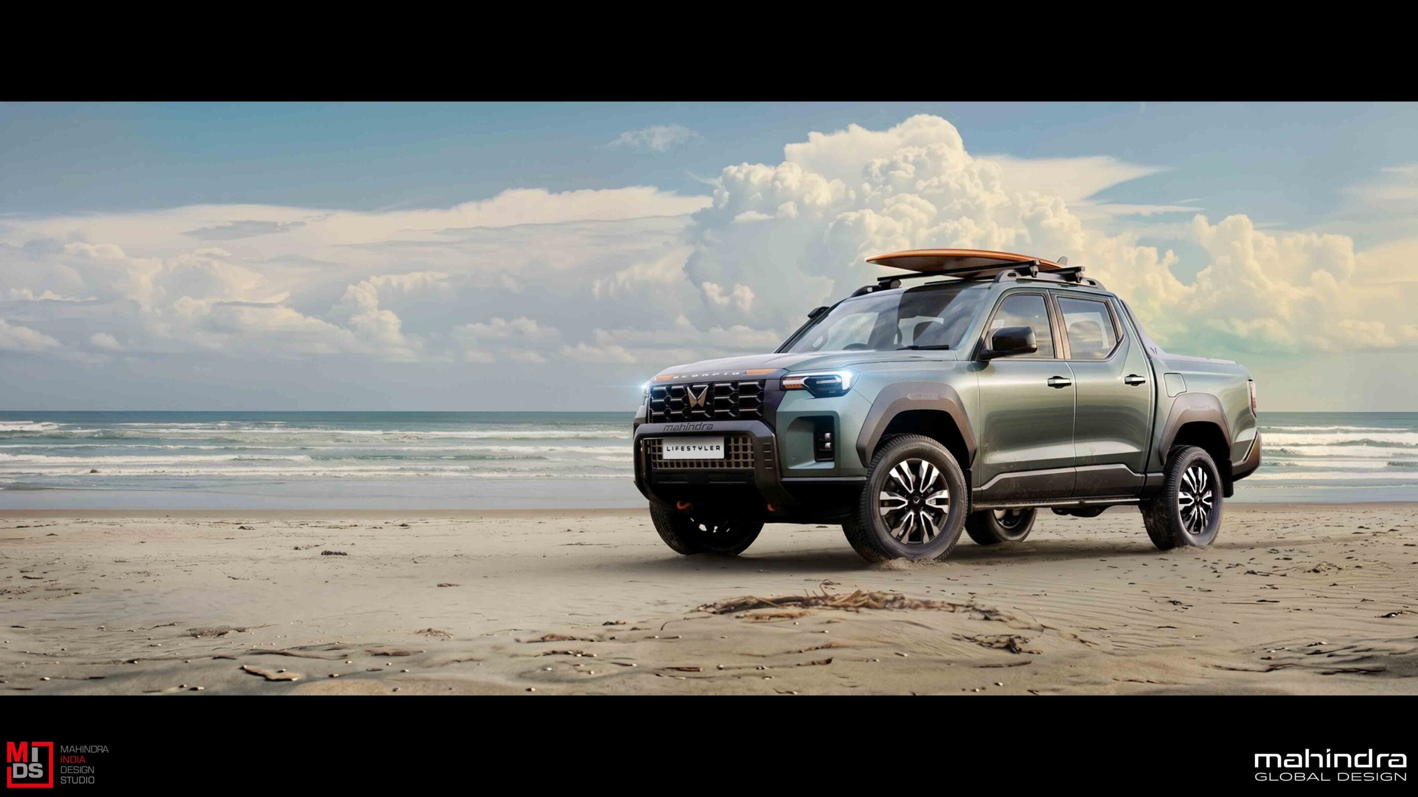 Mahindra pickup parked on a sandy beach with a surfboard on the roof and the ocean in the background