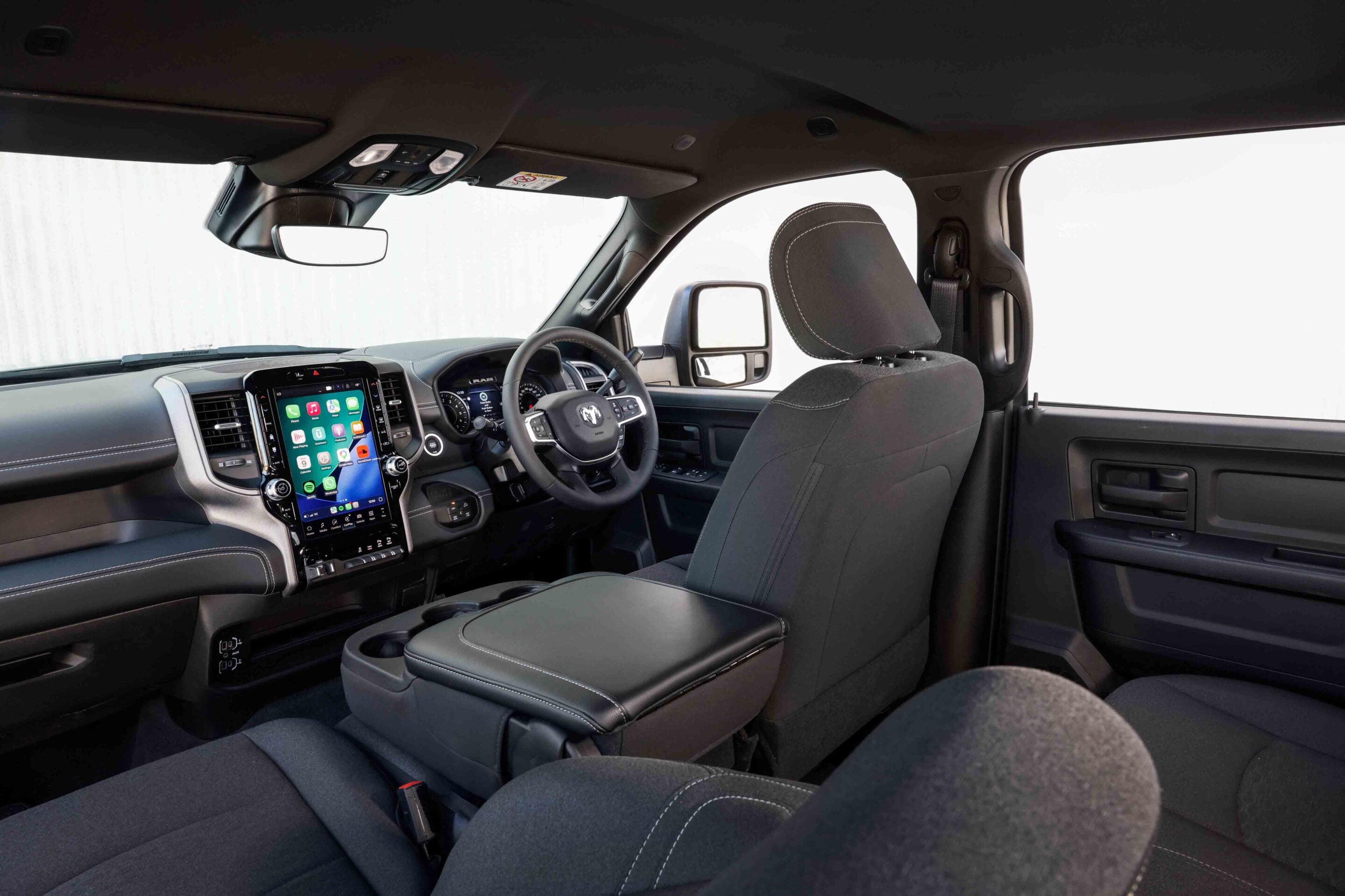 Interior of a modern pickup truck: driver seat, large central touchscreen, steering wheel, and rearview mirror.