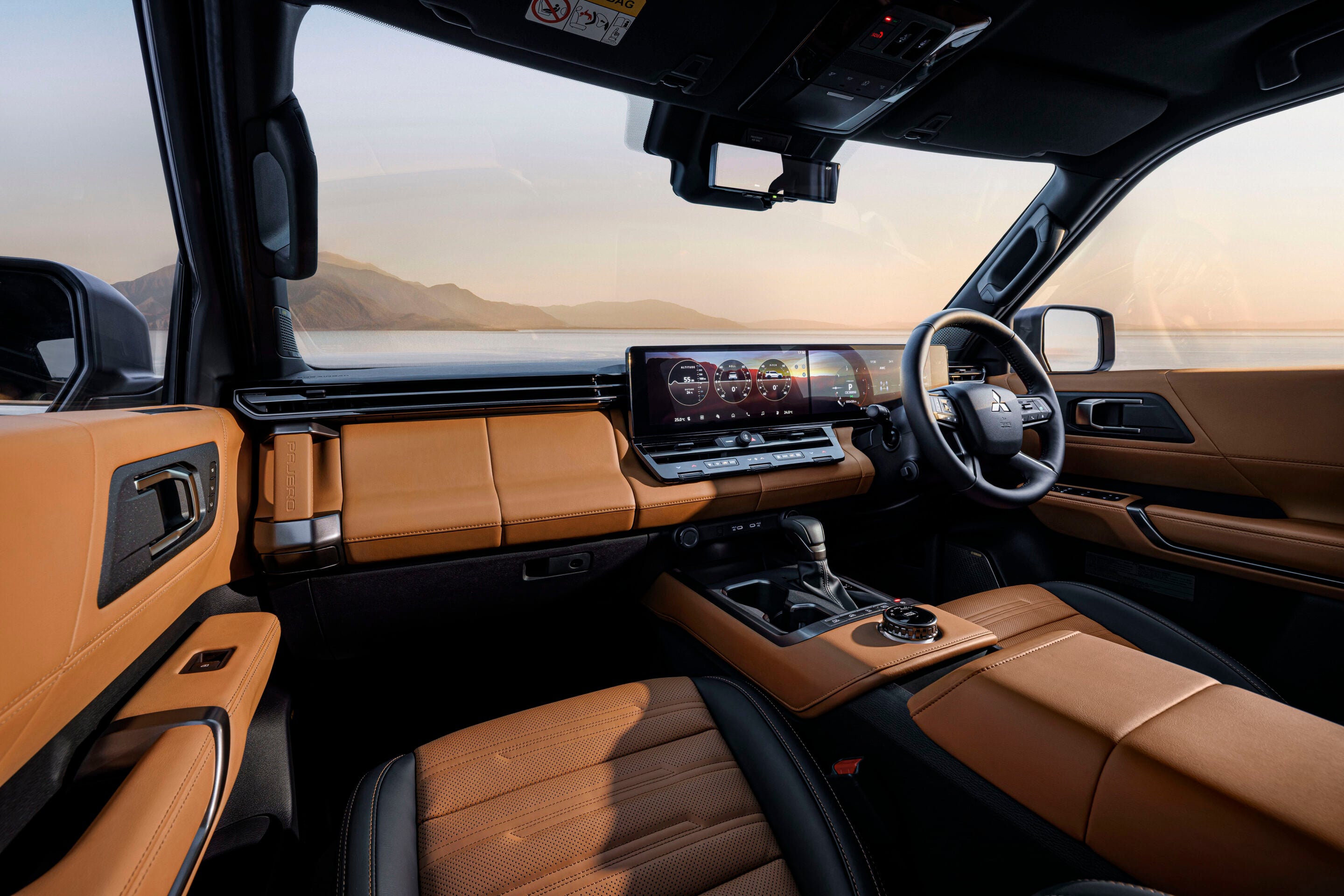 Luxurious car interior with tan leather seats and a digital instrument cluster, mountains visible through the windshield