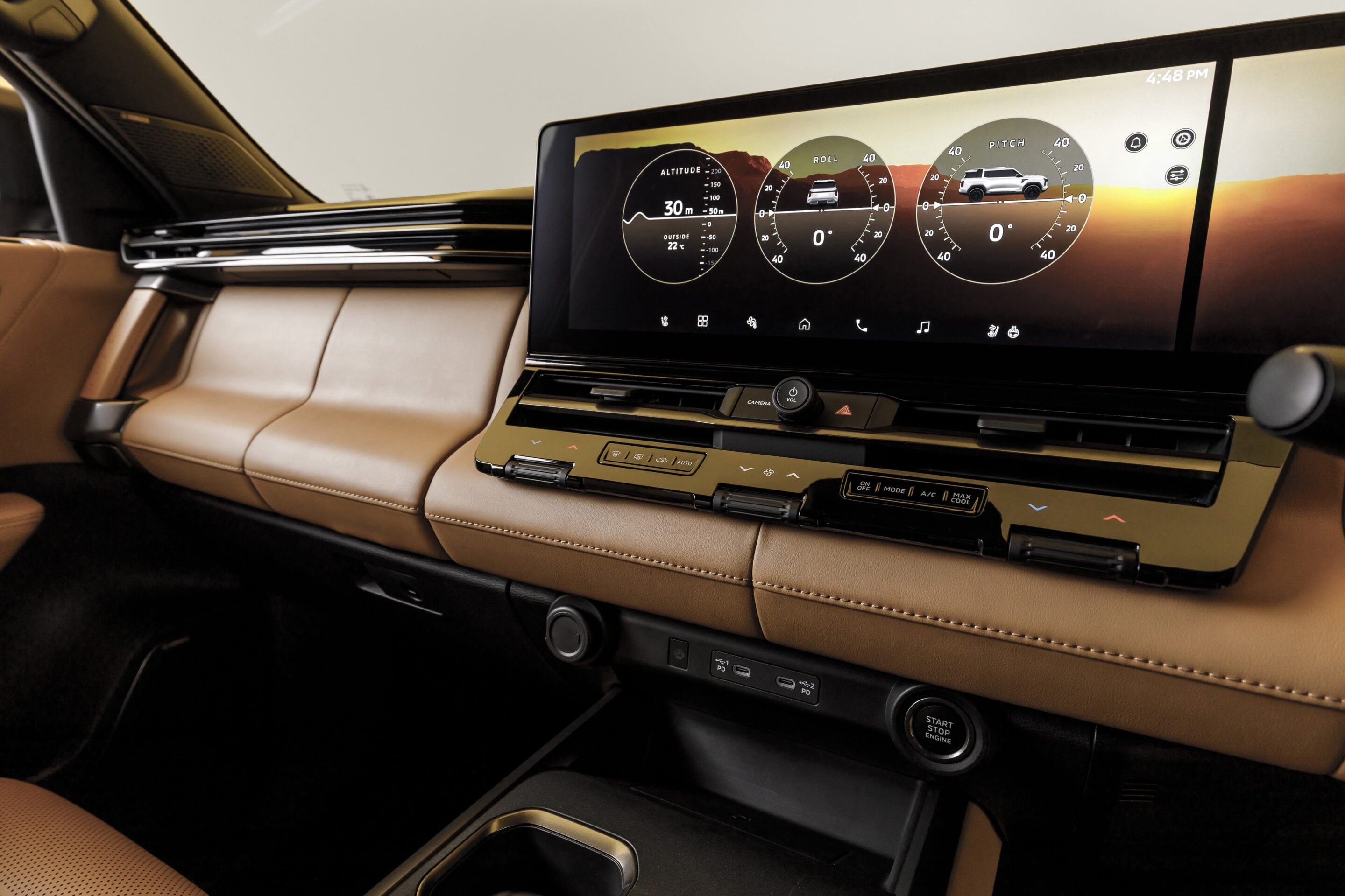 Luxurious car interior with tan leather upholstery and a wide curved digital dashboard displaying vehicle gauges against a sunset background.