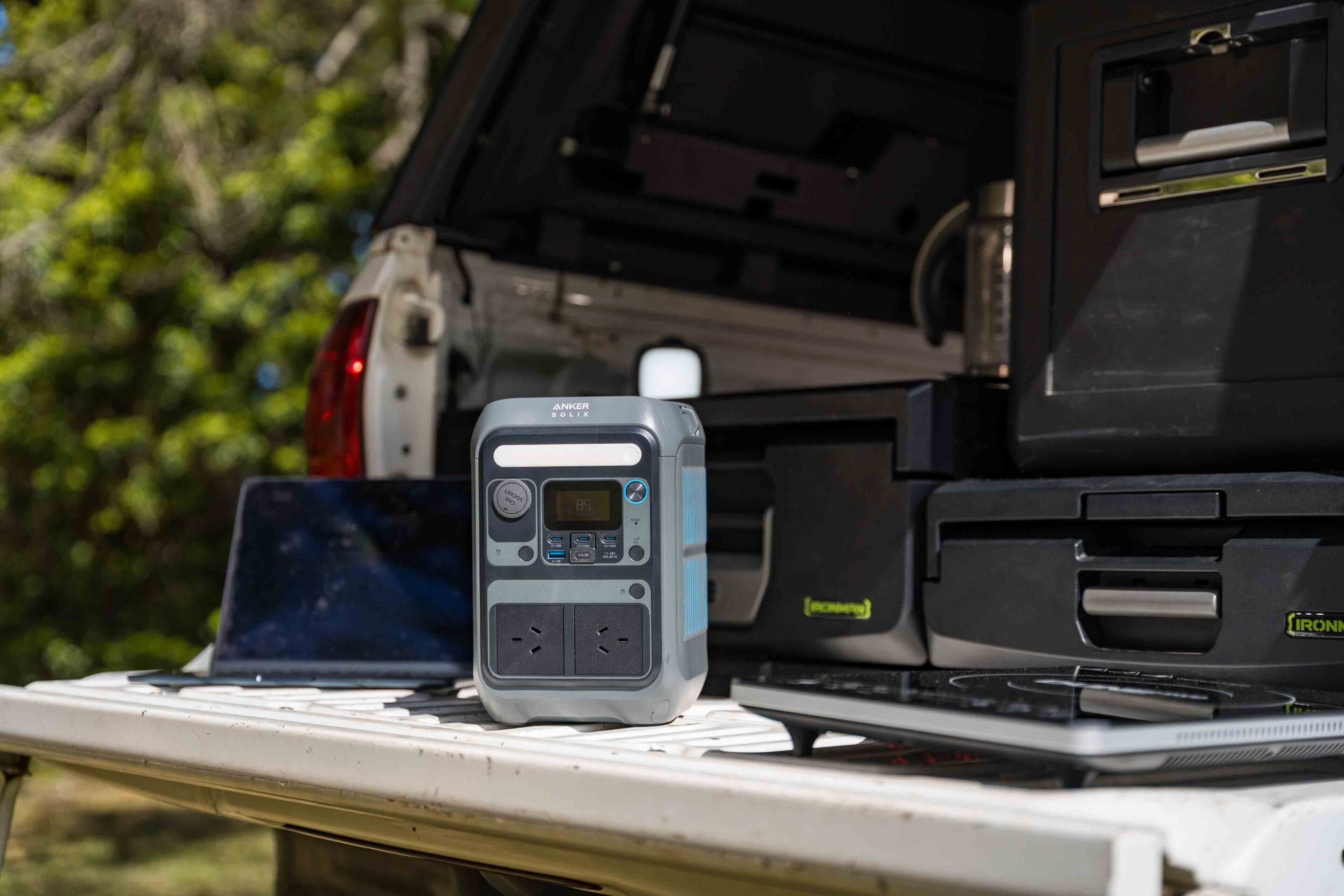 Portable power inverter sits on the tailgate of a pickup truck with truck bed gear in the background.