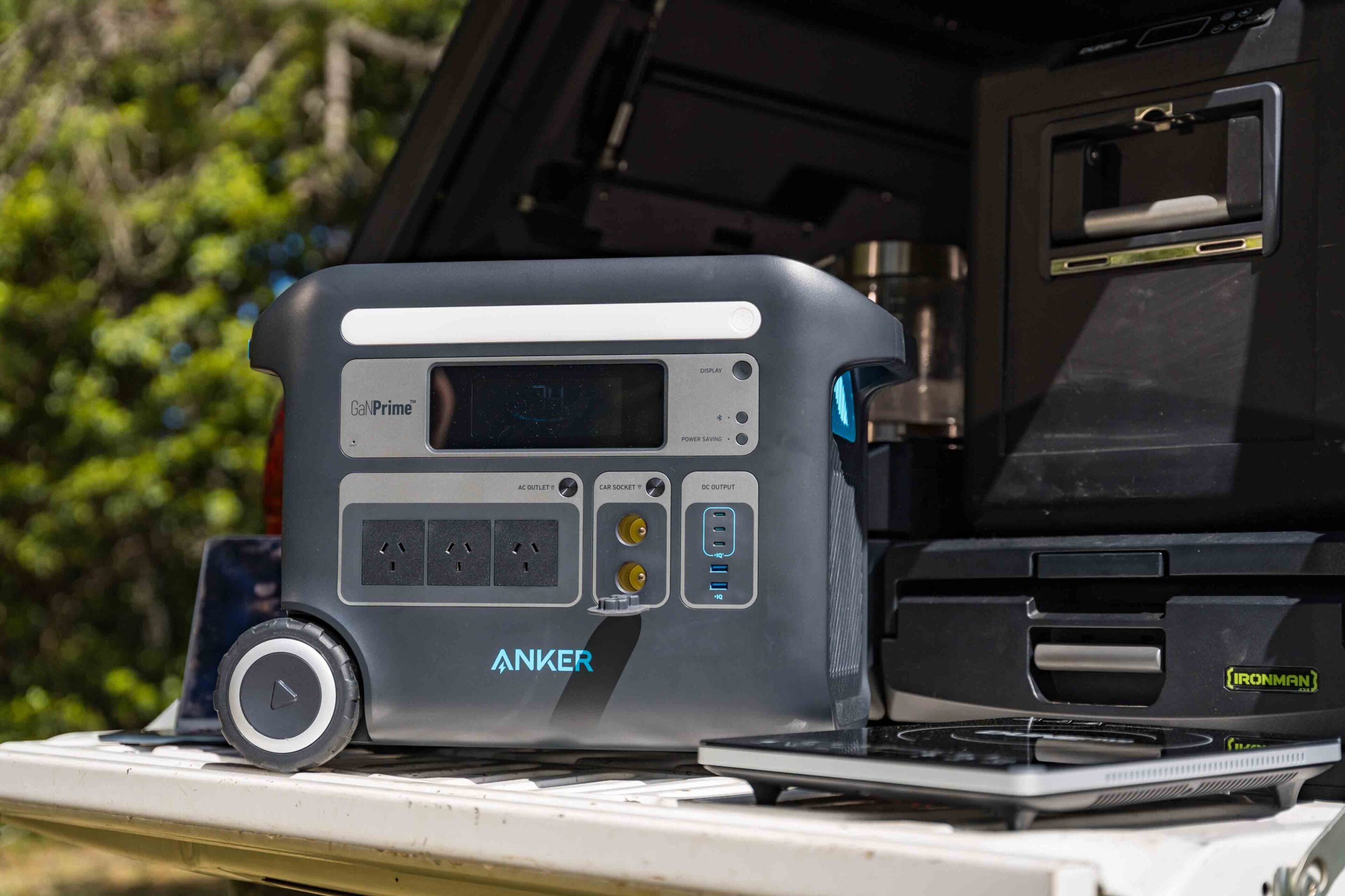 Anker GaNPrime portable power station with multiple outlets and a display placed on a surface outdoors near a vehicle load area.