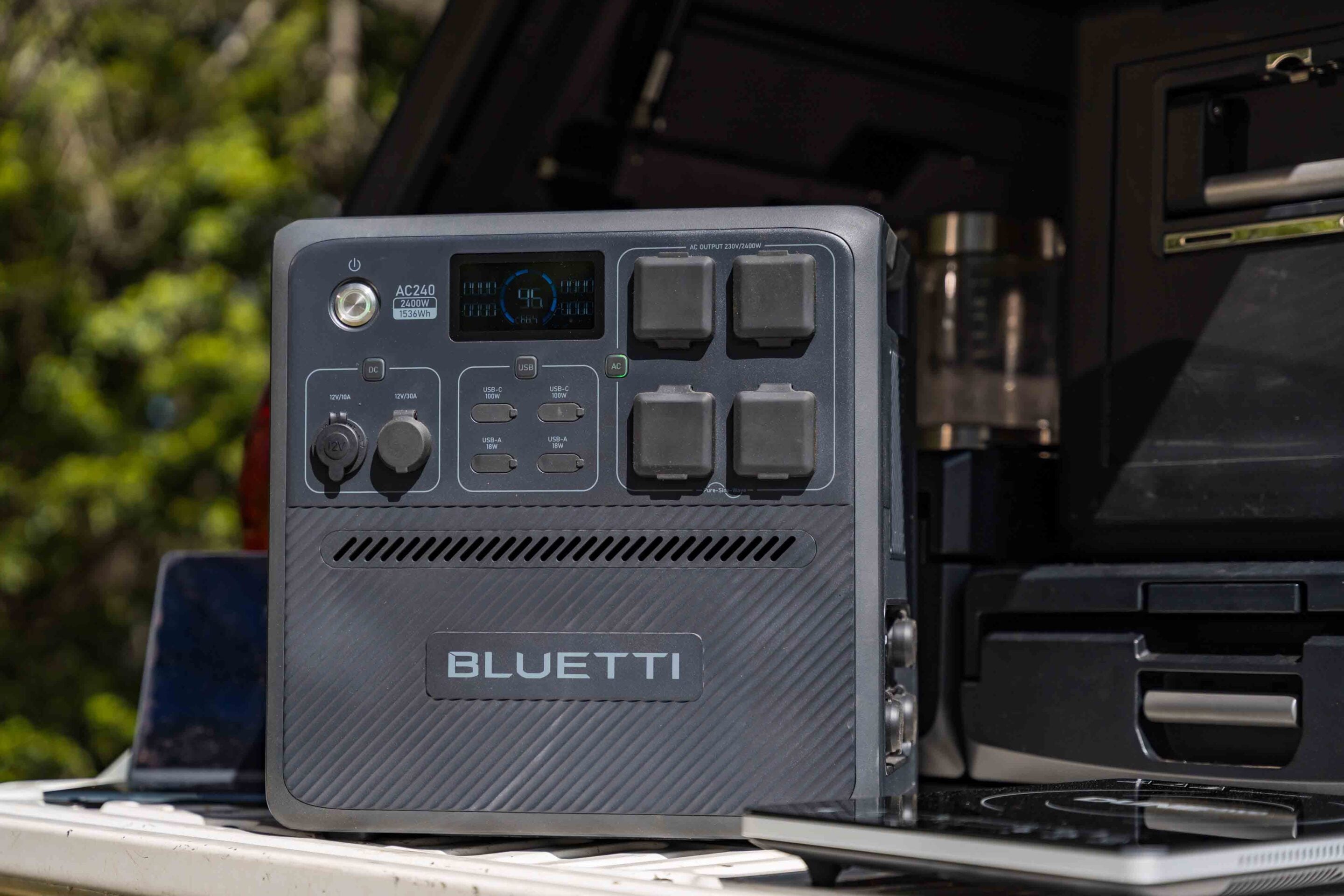 Bluetti portable power station with a circular display and multiple plug outlets, mounted in a vehicle interior.