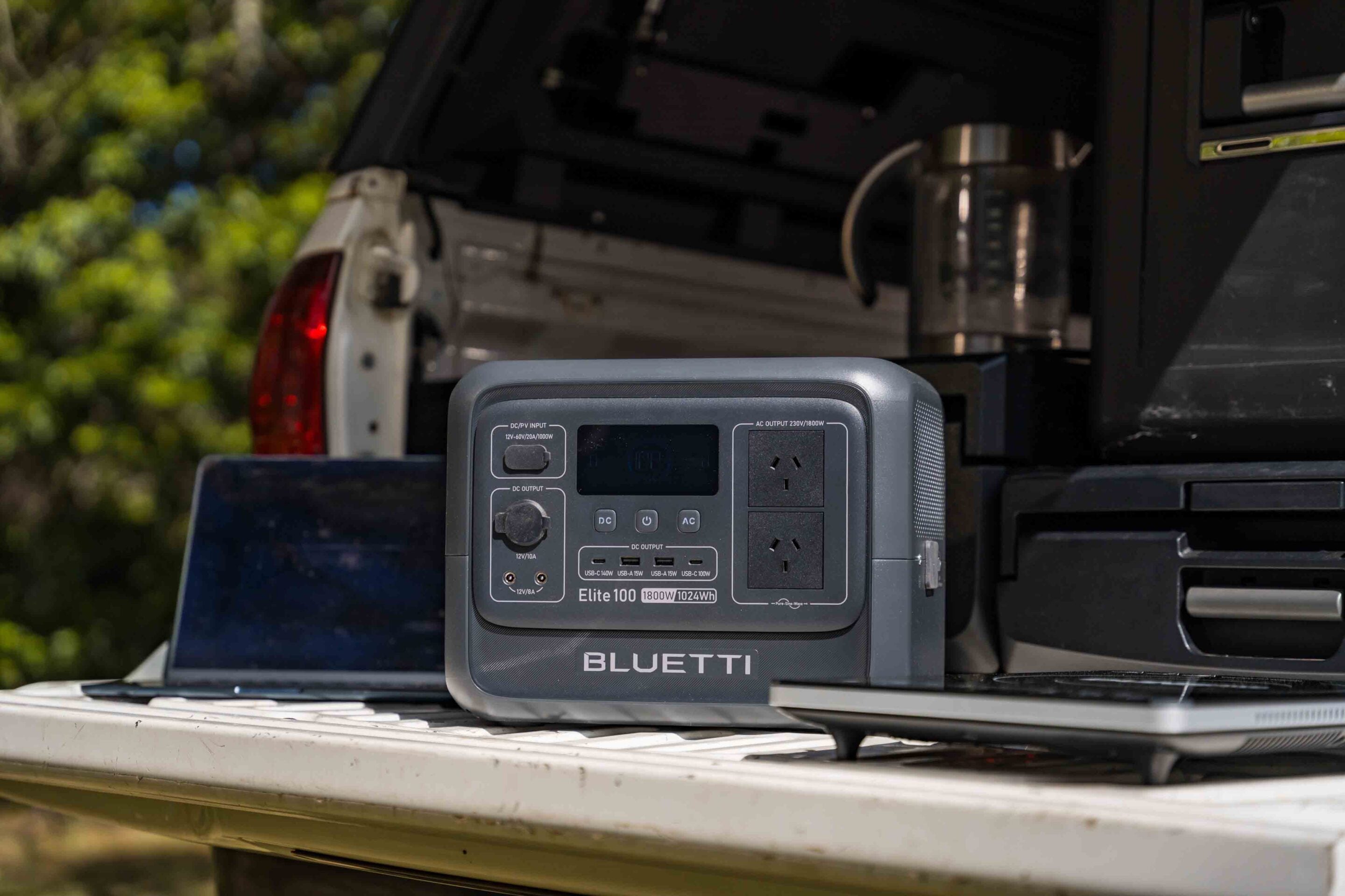 Bluetti Elite 100 portable power station on a truck bed with open tailgate and vehicle in the background.