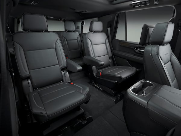 Black leather SUV interior showing three captain’s chairs in the second row, with a center console and cup holders for passengers