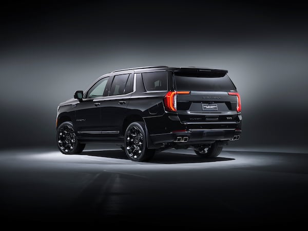 Black full-size SUV photographed from a rear-right three-quarter angle in a studio, highlighting glossy finish, chrome accents, and large dark wheels.