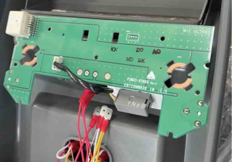 Internal green circuit board with wiring harness and connectors inside an electronic device.
