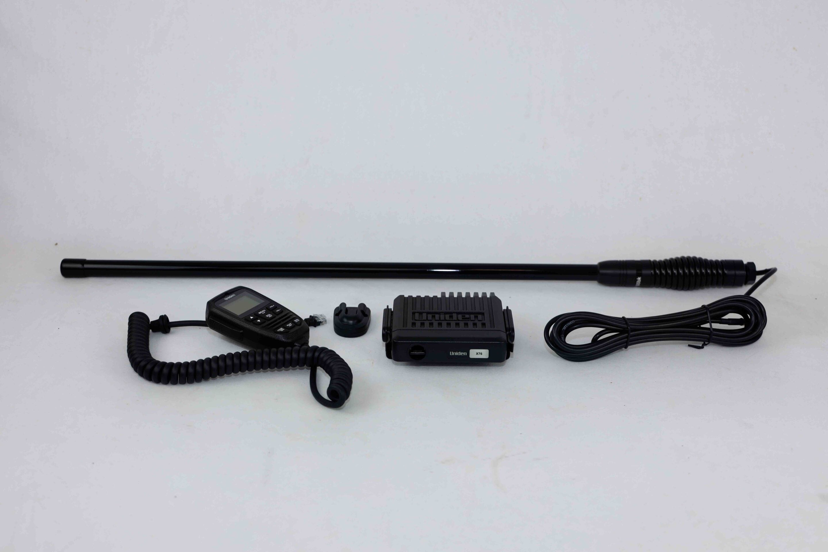 Uniden X76 handheld radio with a long external antenna and accessories on a white surface.